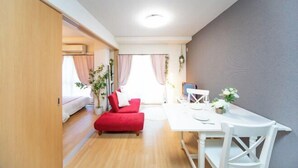 Un espacio habitable compacto con zona de comedor, un sofá rojo y una mesita.
