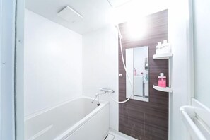Een badkamer met een bad, douche en een spiegel.