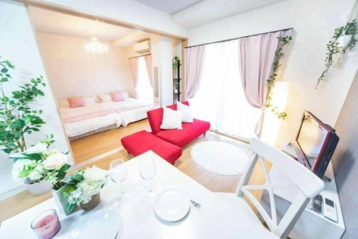 Een moderne hotelkamer met een bed, rode bank, eettafel en witte stoelen.