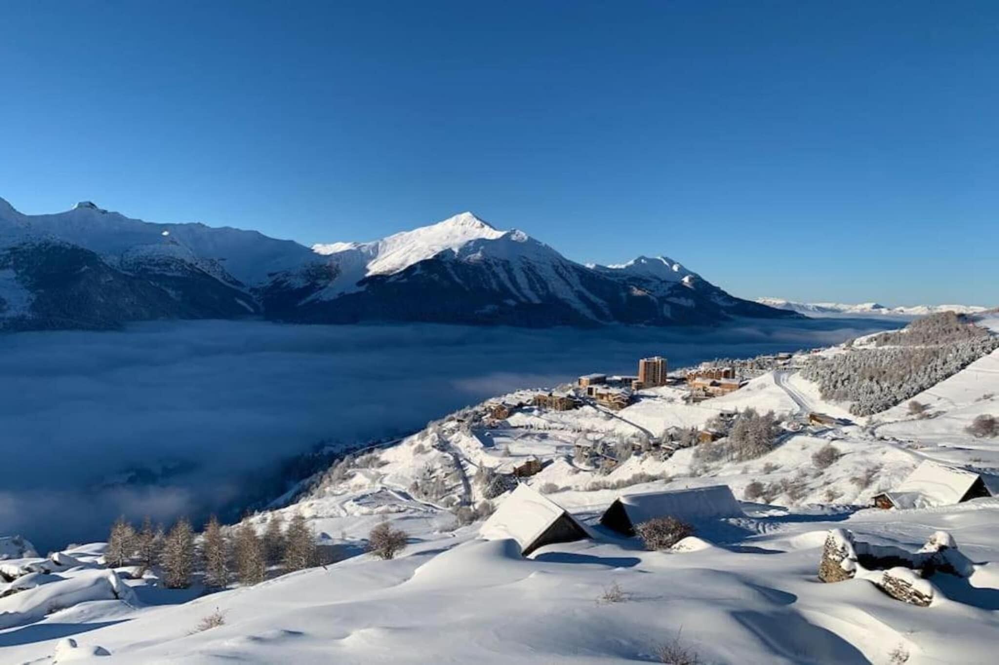 Un paisaje montañoso nevado con un pueblo enclavado en el valle.