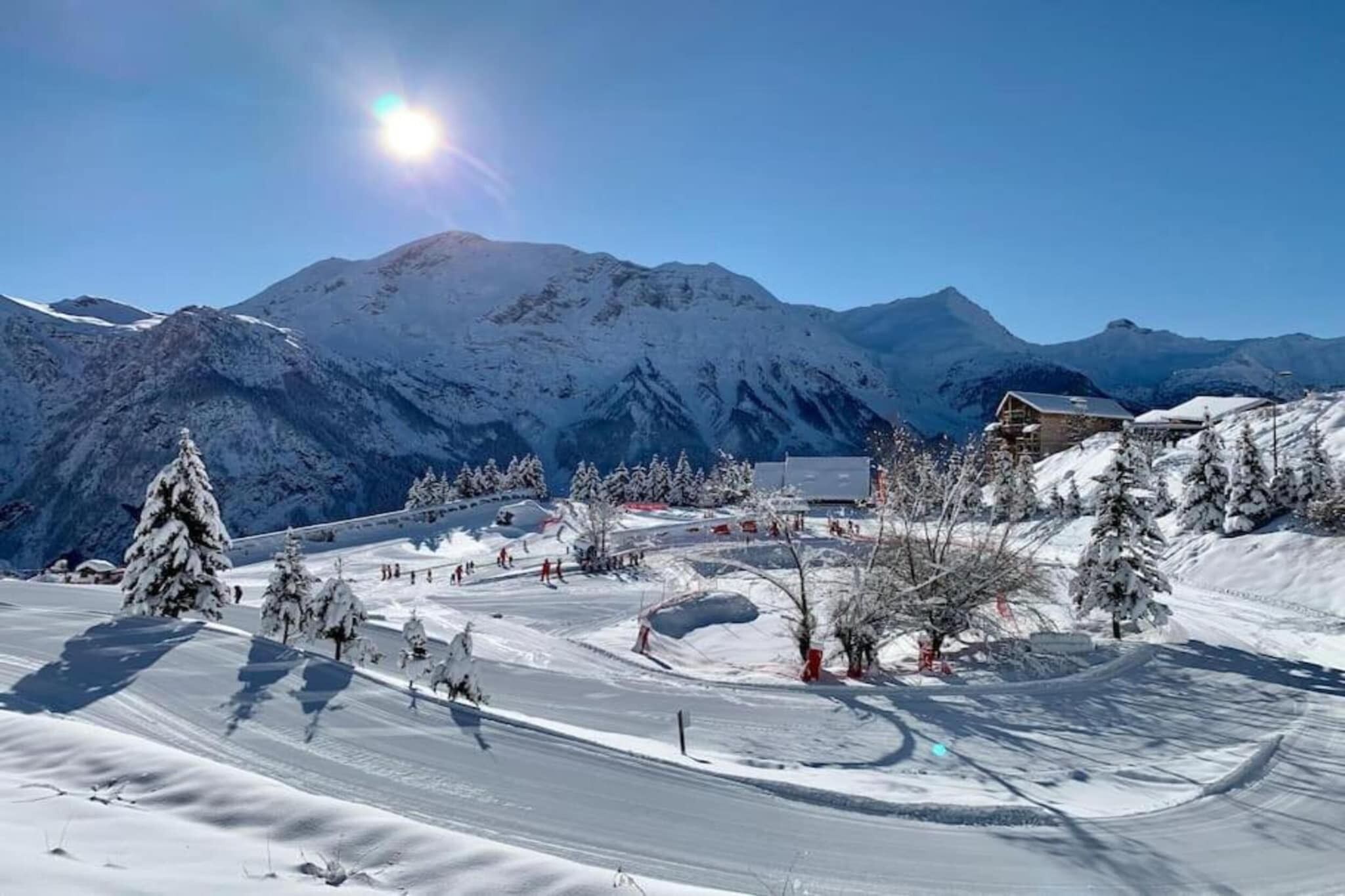 A snow-covered ski resort with a mountain backdrop, ski slopes, and a lodge.