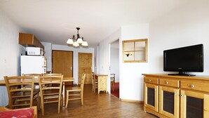 A compact living space with a dining area, kitchenette, and a television on a wooden cabinet. - Apartment in Orcières with Ski Slope Access (Orcières)
