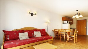 A cozy living area with a wooden sofa, a small wooden table, and a dining set. - Apartment in Orcières with Ski Slope Access (Orcières)