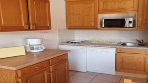 A kitchen with wooden cabinets, a microwave, a coffee maker, and a dishwasher. - Alpine Apartment for 8 guests (Les Deux Alpes)