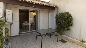 Ein Patio mit Glastür, einem Tisch und einem Blumentopf.
