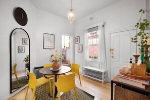 A dining area with a round table, yellow chairs, a mirror, and a hanging light fixture. - Smith 20 Collingwood Melbourne (Collingwood)