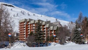 Un hotel de varios pisos con un diseño arquitectónico moderno, situado en una zona montañosa nevada.