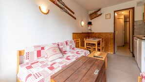 A cozy room with a wooden sofa, a wooden table, and a kitchen area with a coffee machine. - Apartment in Morillon near Ski Resort (Morillon)