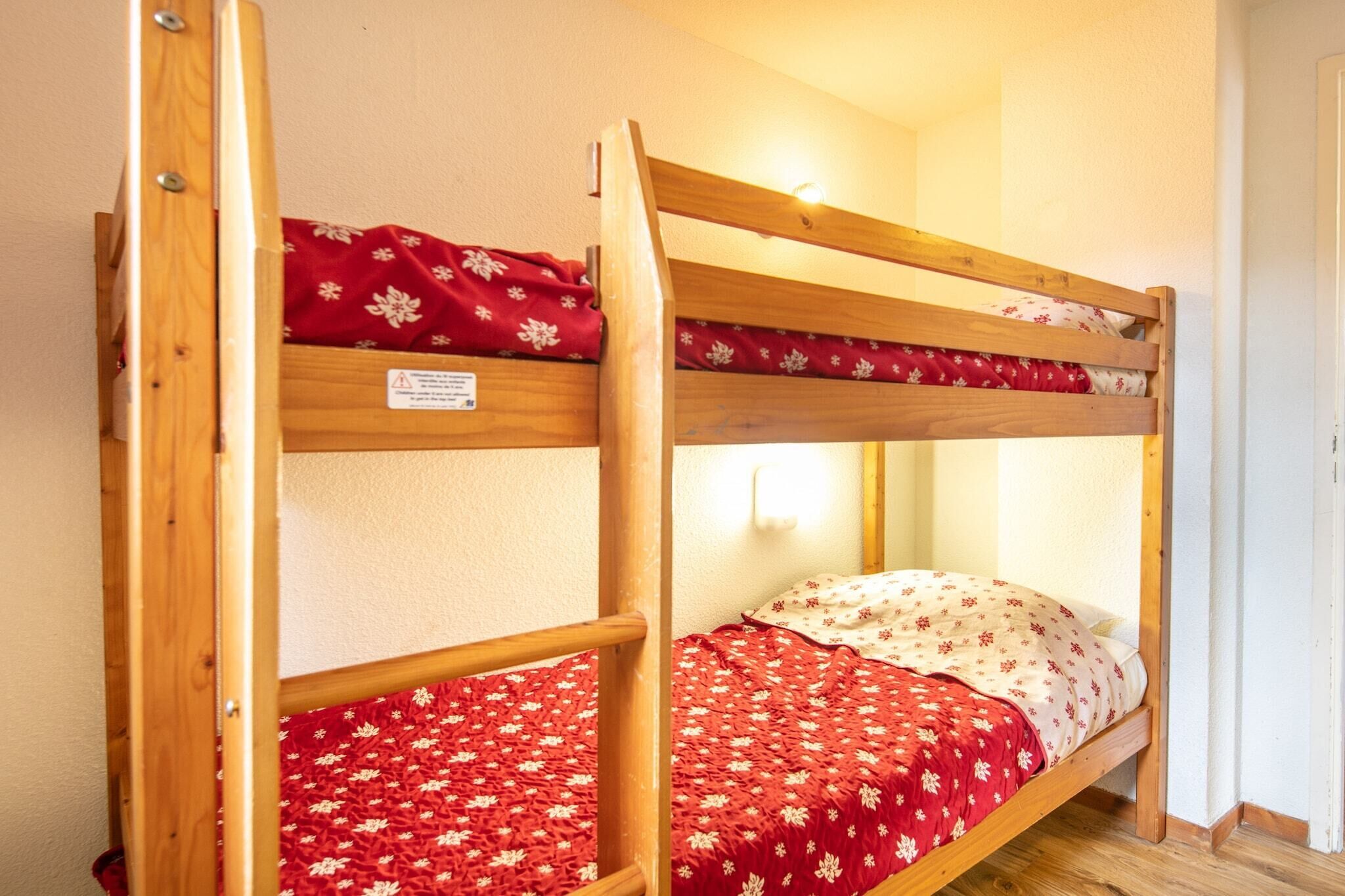 Un lit superposé avec une literie à motifs floraux rouges et une structure en bois.