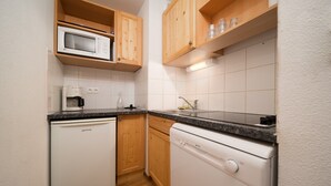 Een kleine keuken met een magnetron, koffiezetapparaat en vaatwasser.