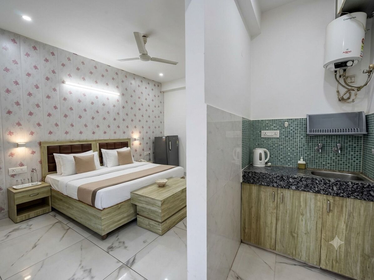 Une chambre à coucher comprenant un lit, des tables de chevet, un ventilateur de plafond, ainsi qu’une salle de bain avec un lavabo, un miroir et un porte-serviettes.