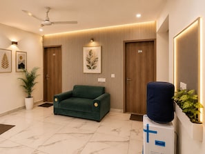 A modern hotel lobby with a green sofa, a ceiling fan, and a wall-mounted plant. - Akshay Dream Stay (Gurugram)
