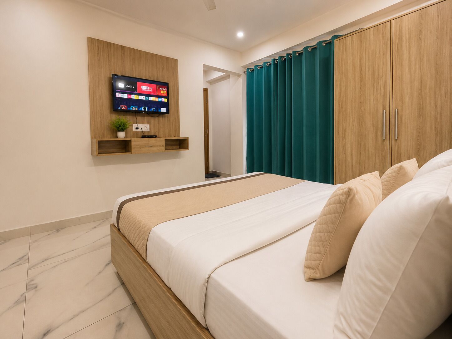 Una camera da letto con un letto, una TV a parete, un armadio in legno e tende color acquamarina.
