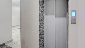 An elevator with a digital display and a marble border. - Akshay Dream Stay (Gurugram)