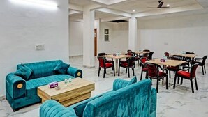 A spacious room with teal sofas, a wooden coffee table, and red chairs. - Akshay Dream Stay (Gurugram)