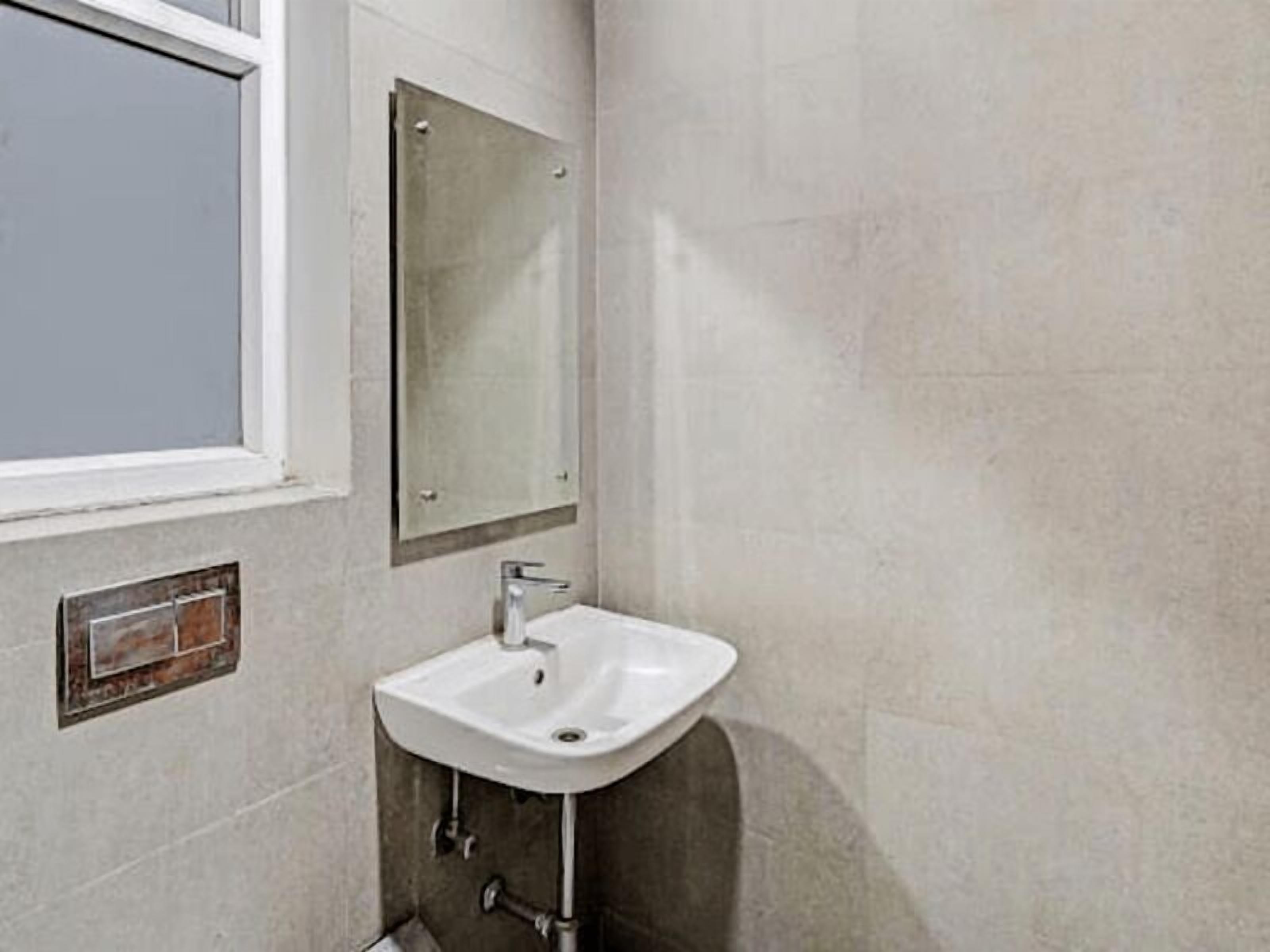A bathroom with a white sink, a mirror, and a window.