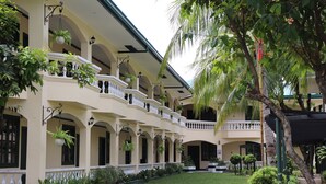 A multi-story building with balconies, hanging plants, and a well-maintained garden.