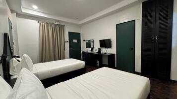 Een hotelkamer met twee eenpersoonsbedden, een bureau met een computer en een flatscreen televisie, een garderobe en een spiegel.