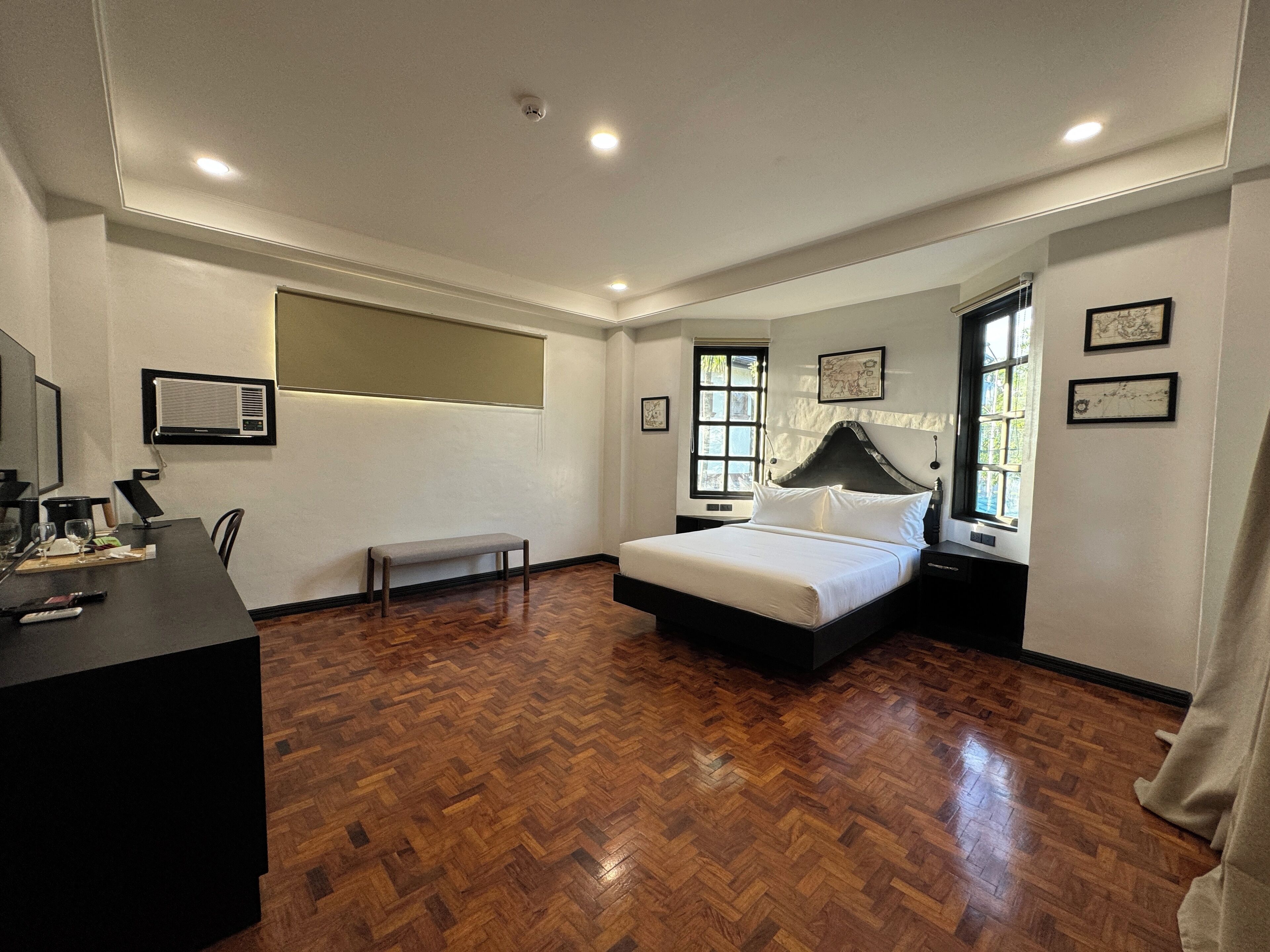 A bedroom with a bed, a bench, a desk with a chair, and a window.