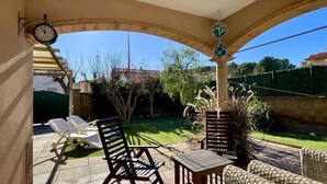 A covered patio area with outdoor furniture, a clock, and a decorative hanging ornament. - Casa LiaRAMBLA MALLOLS 9, CASA LIA (L'Escala)