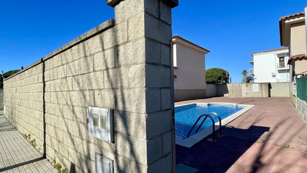 A swimming pool adjacent to a building with a stone wall and a tiled walkway. - Casa LiaRAMBLA MALLOLS 9, CASA LIA (L'Escala)