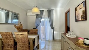 A dining area with wicker chairs, a wooden table, a hanging light fixture, and a view through sheer curtains to an outdoor space. - Casa LiaRAMBLA MALLOLS 9, CASA LIA (L'Escala)