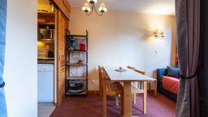A compact kitchen with a microwave, shelves, and a table with chairs.