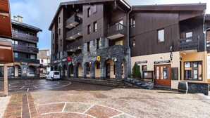 A multi-story building with a stone facade, balconies, and a paved courtyard.