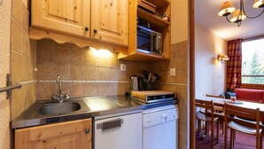 A compact kitchen with wooden cabinets, a built-in microwave, and a dishwasher.