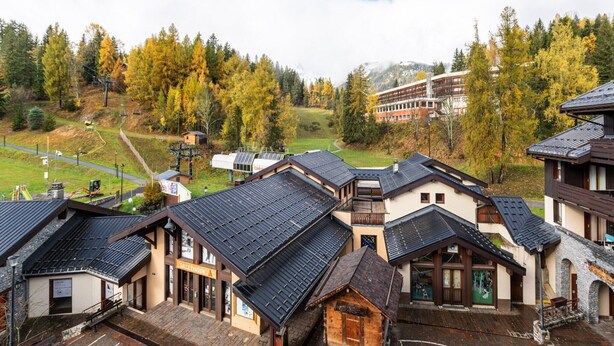 A traditional chalet-style building with a steeply pitched roof, a wooden facade, and a visible entrance.