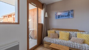 A cozy room with a wooden bed, a bench, and a view of a wooden building outside. - Sunny Mountain Retreat (Orcières)