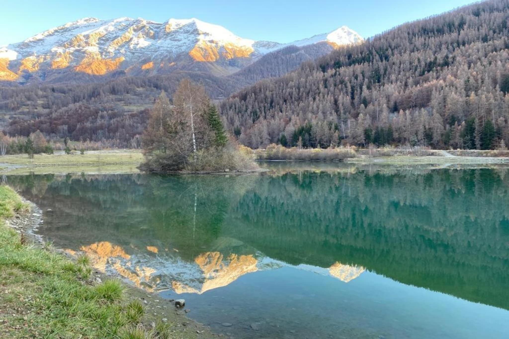A serene lake with a mountain backdrop, surrounded by forested hills.