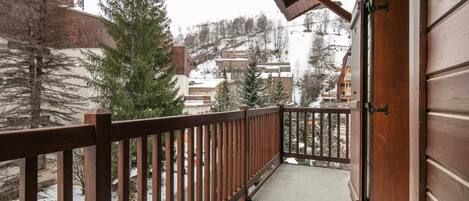 Ein Balkon mit Holzbalkon, der einen verschneiten Ort mit Häusern und Bäumen überblickt.