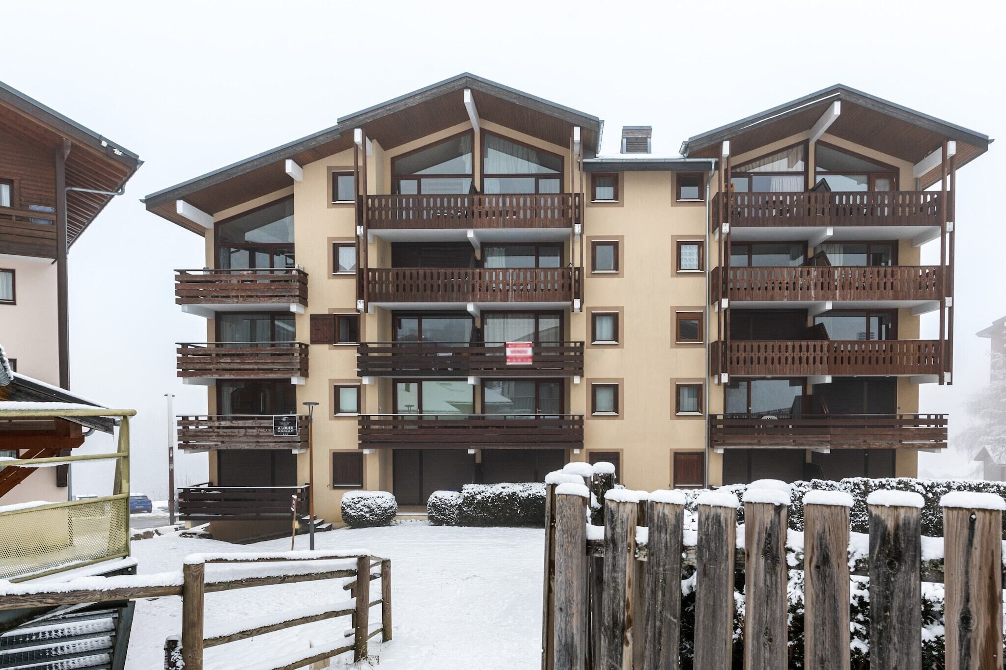 A multi-story building with balconies, a sign indicating a location, and snow on the ground.