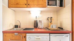 A compact kitchen with wooden cabinets, a microwave, a coffee maker, and a dishwasher. - Terrace Apartment in Chamrousse (Chamrousse)