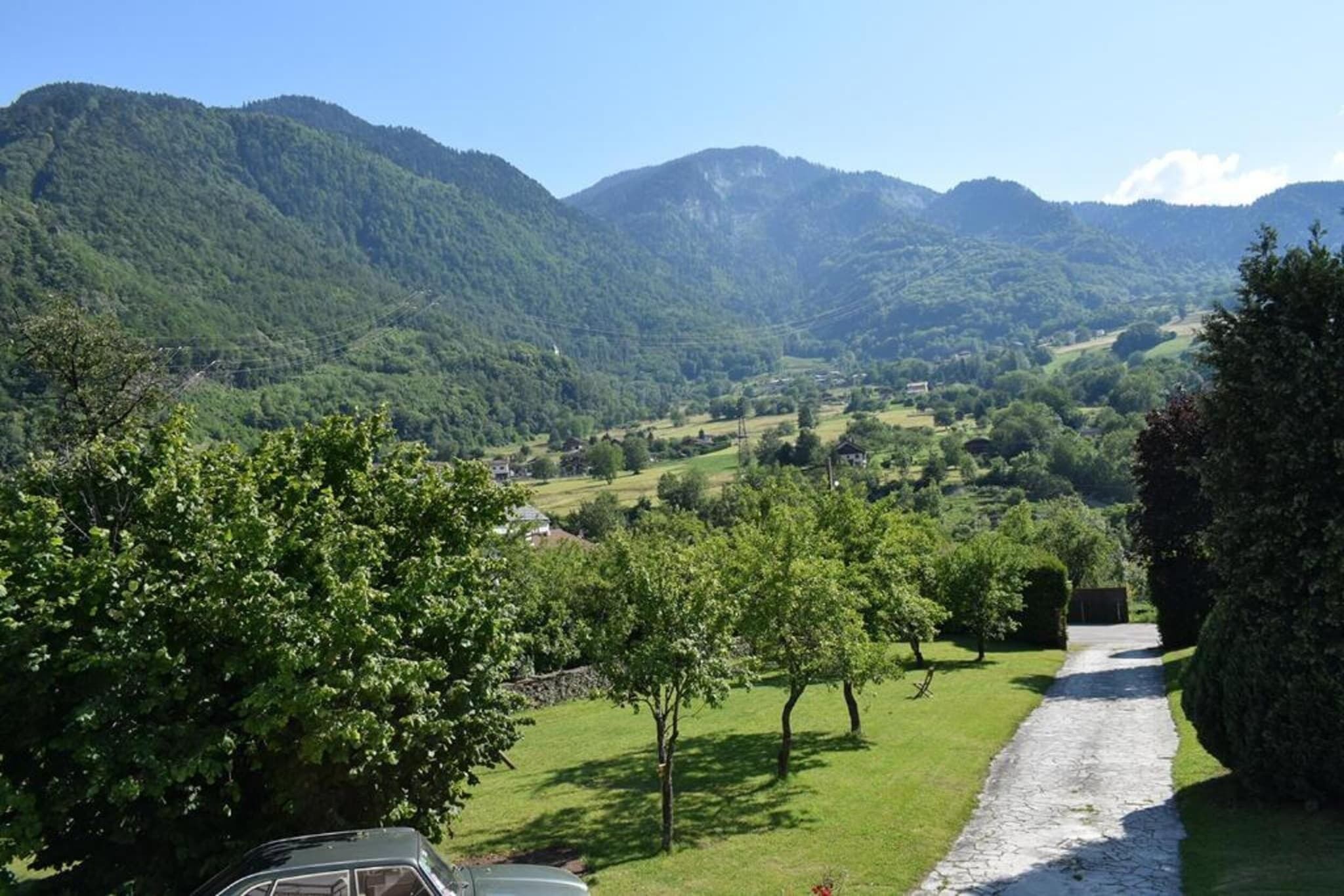 A rural landscape with a stone pathway leading through a green valley surrounded by hills.