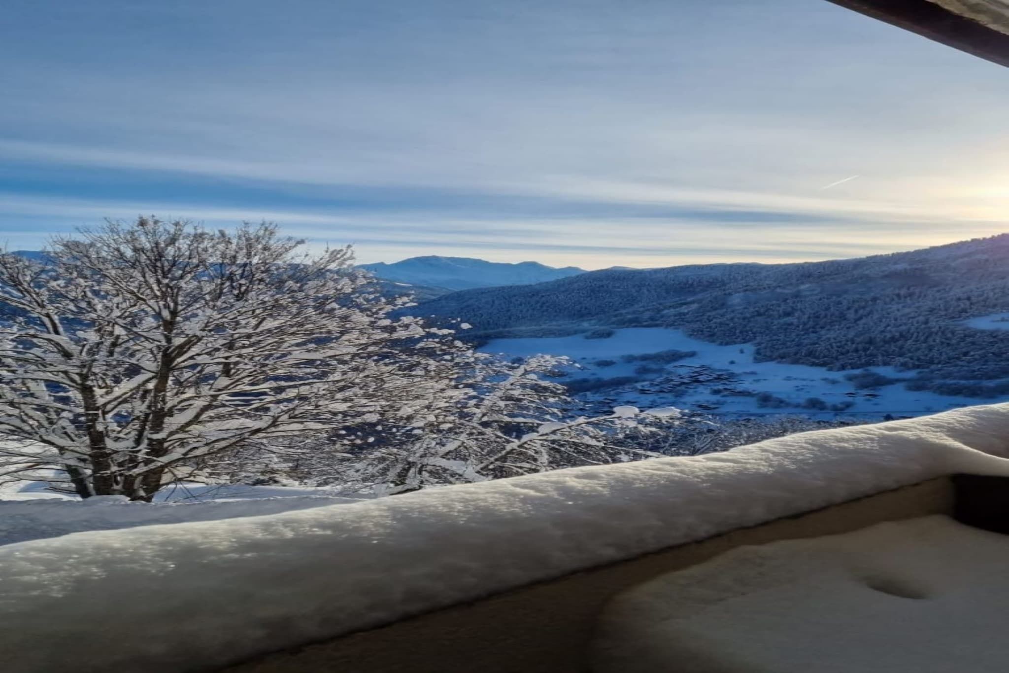 A snow-covered landscape with a view of a valley and mountains.