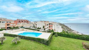 Un quartier résidentiel situé sur la côte, doté d’une piscine entourée de pelouses et de haies bien entretenues.