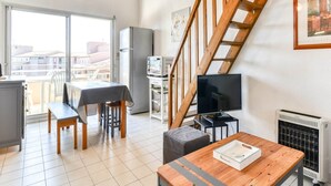 Un appartement moderne comprenant un coin repas, un téléviseur et un escalier.