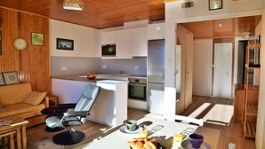Un espacio habitable compacto con kitchenette, zona de comedor y área de estar.