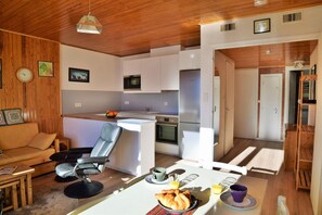 Un espacio habitable compacto con kitchenette, zona de comedor y área de estar.