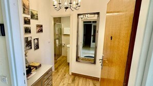 Um corredor com piso de madeira, um espelho sobre a penteadeira e um lustre.