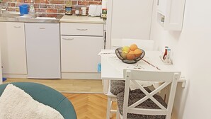 Uma cozinha compacta com micro-ondas, geladeira e uma TV presa acima do balcão.