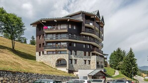 A multi-story hotel with balconies, stone facade, and a view of the surrounding landscape.