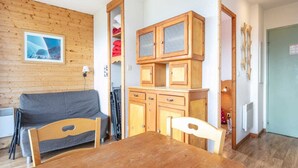 Ett rum med träpanel på väggarna, en soffa, ett matbord och ett skåp med glasdörrar.