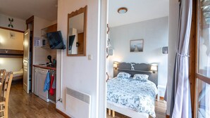 Une petite chambre comprenant un lit, un bureau, un miroir et un téléviseur.