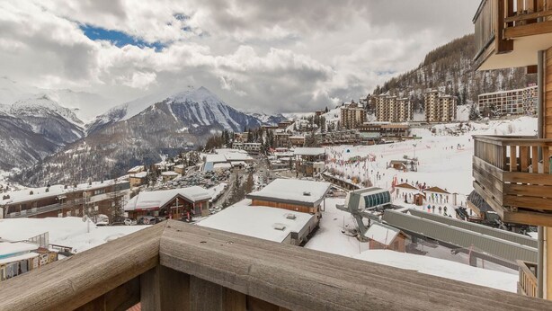 Un pueblo cubierto de nieve en la montaña, con edificios y una pista de esquí.