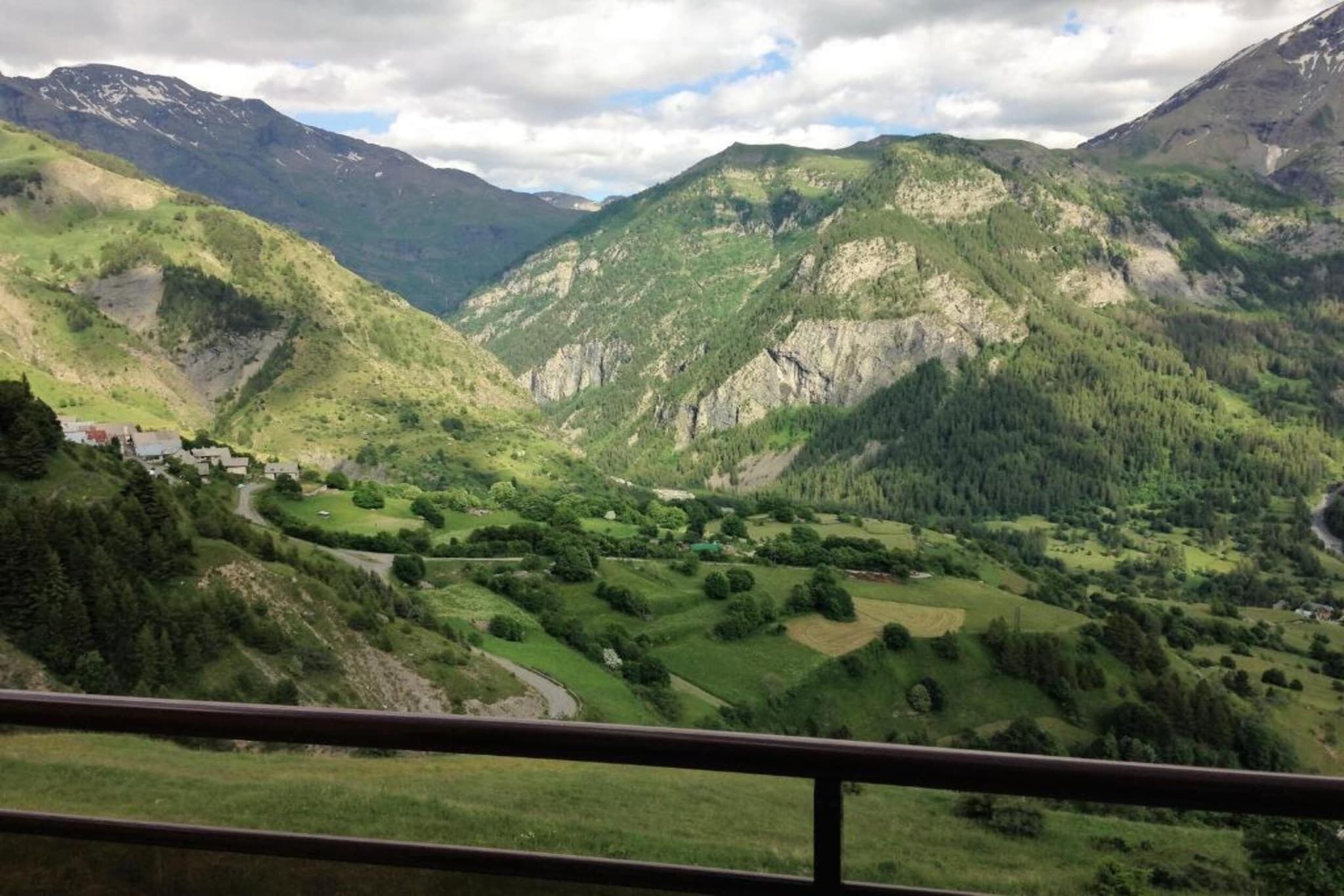 A mountainous landscape with a valley, a small settlement, and a river.