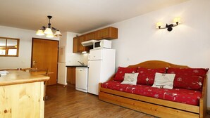 A compact kitchen with wooden cabinets, a white refrigerator, and a wooden dining table.
