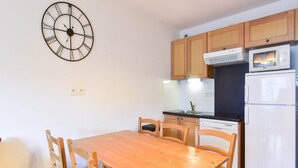 Une cuisine compacte avec des meubles en bois, un four à micro-ondes encastré et un réfrigérateur.